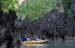 Canoe passengers pass jagged karst rock formations along a sheltered channel in Phang Nga Bay.