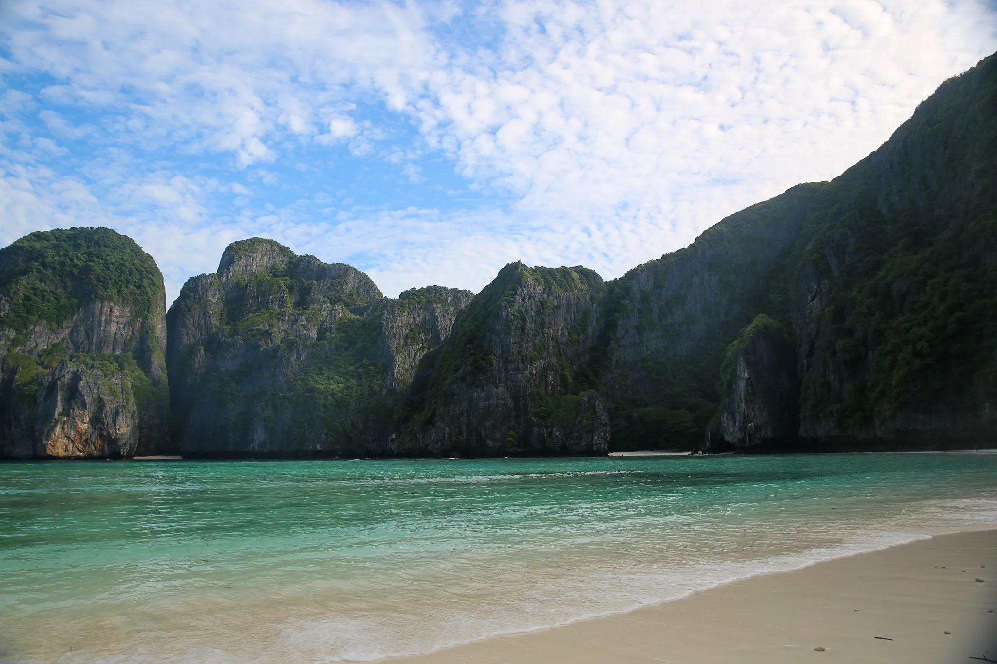 White sand beach at Maya Bay ringed by towering limestone cliffs on Phi Phi Leh island.