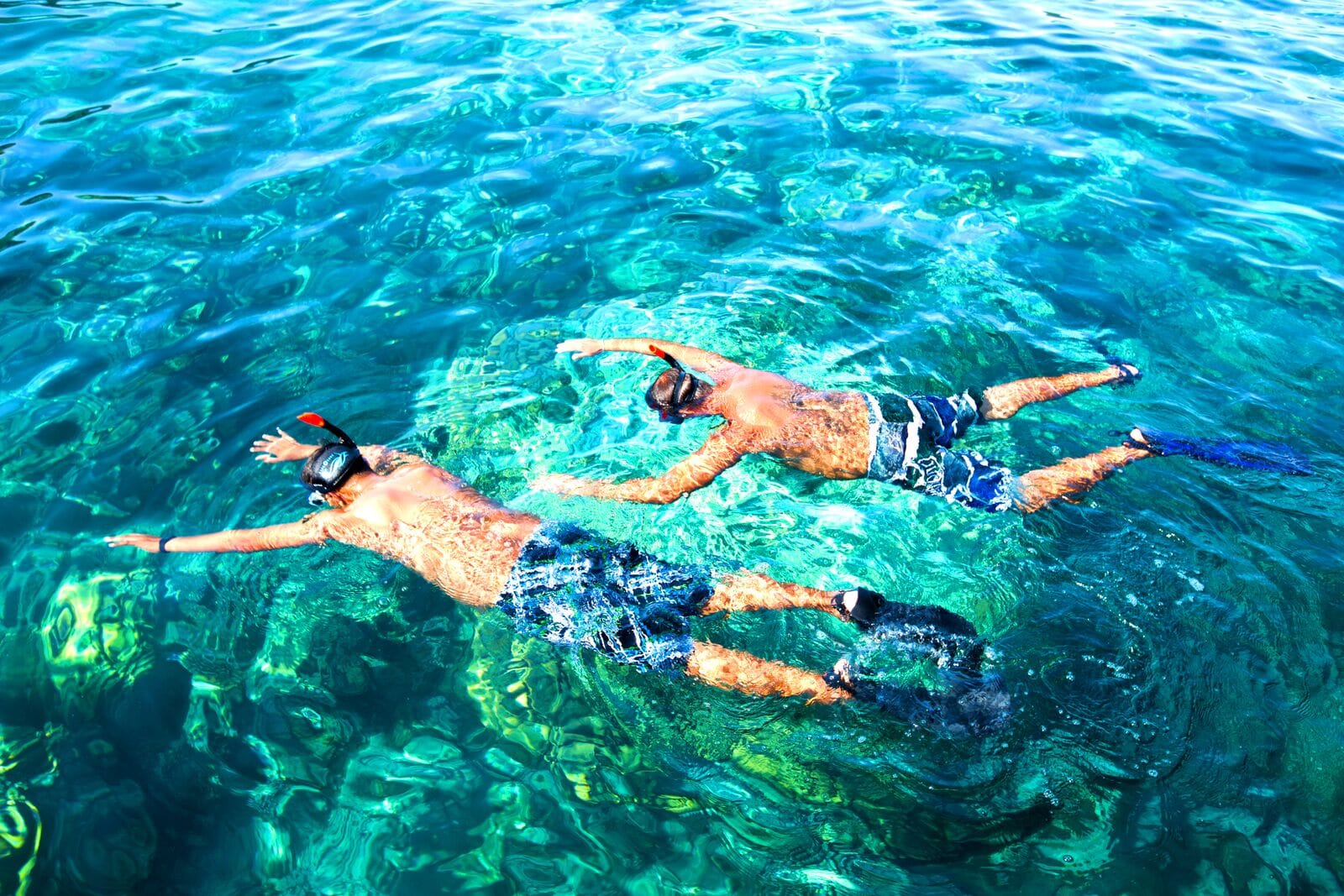 Two snorkellers float side by side in the clear turquoise water off the Phi Phi Islands.