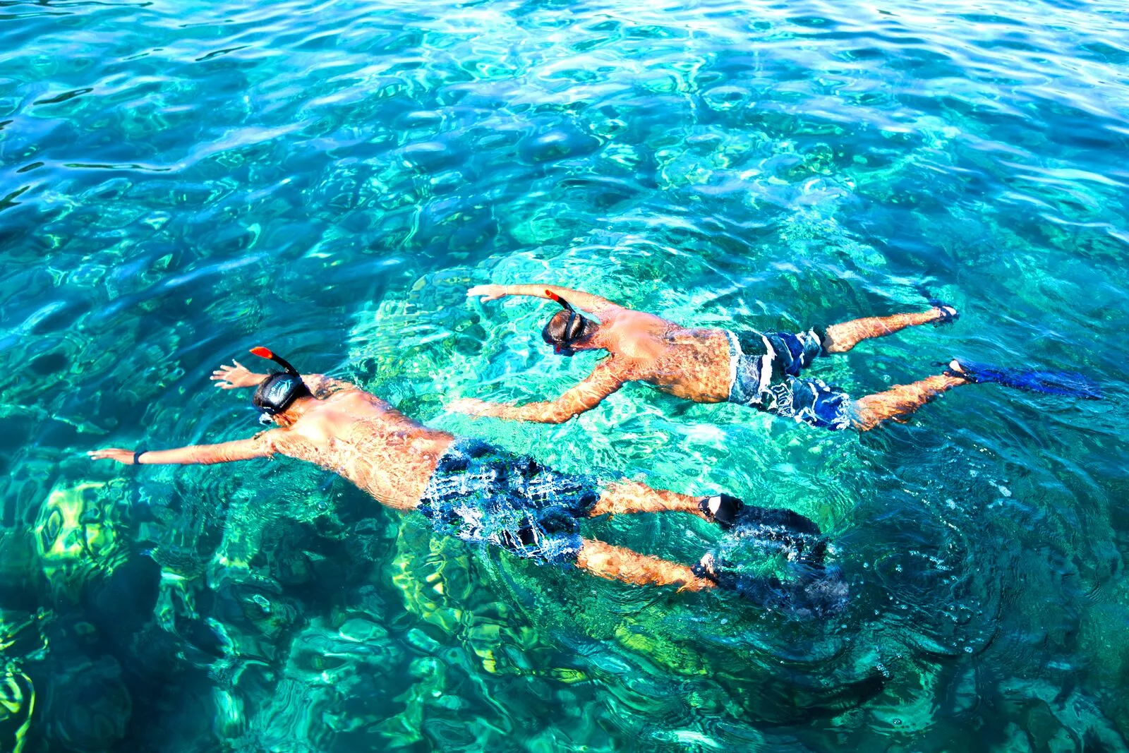 Two snorkellers float side by side in the clear turquoise water off the Phi Phi Islands.