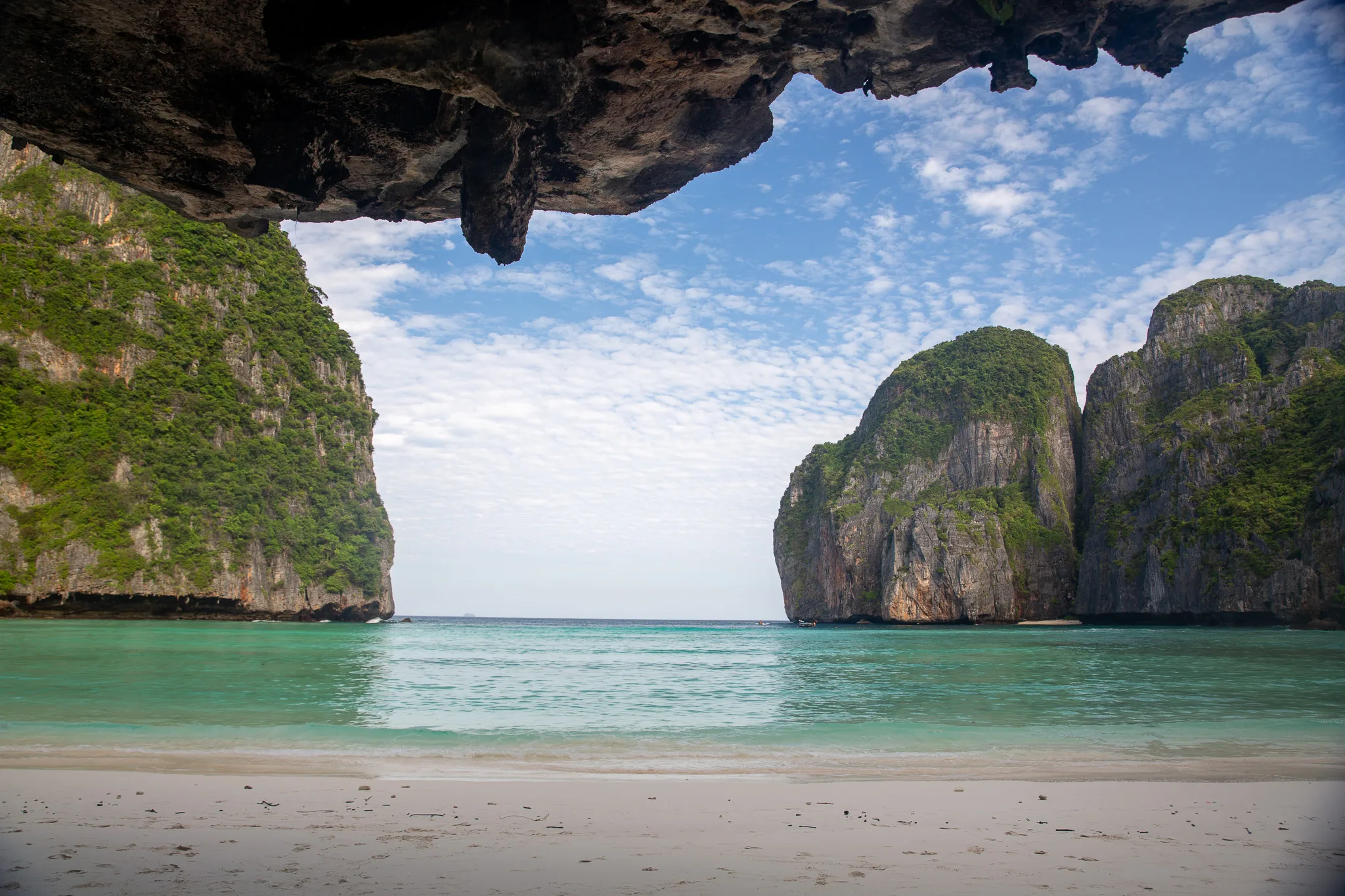 View through a natural rock arch to the limestone karsts and calm sea at Phi Phi Leh.