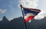 The Thai flag flying from the stern of a longtail boat crossing Cheow Lan Lake in Khao Sok National Park
