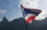 The Thai flag flying from the stern of a longtail boat crossing Cheow Lan Lake in Khao Sok National Park