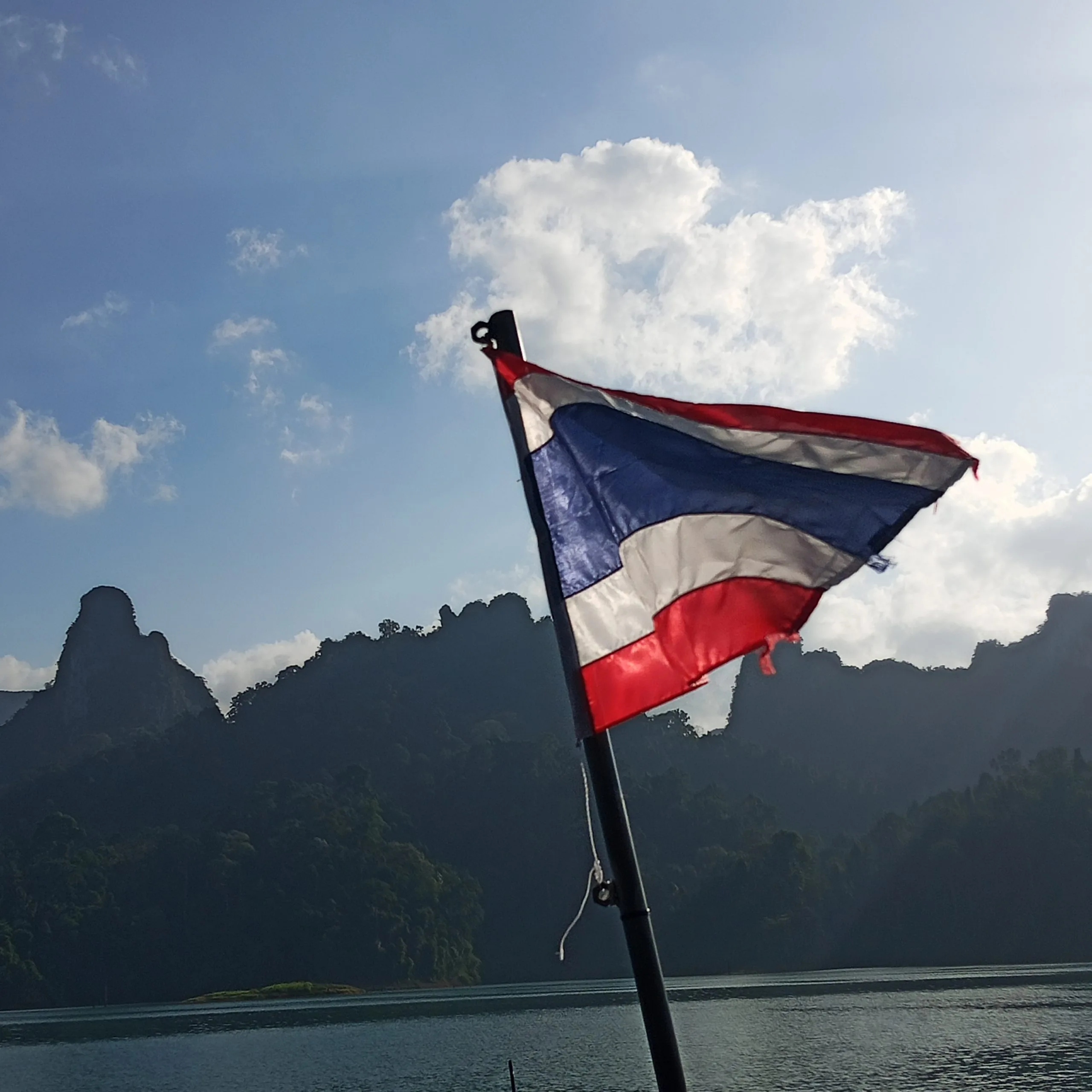 The Thai flag flying from the stern of a longtail boat crossing Cheow Lan Lake in Khao Sok National Park