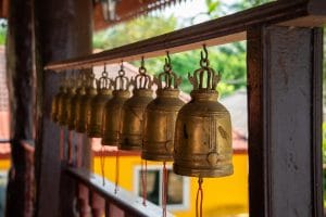 Rangée de cloches de mérite en laiton le long d'une allée de temple bouddhiste près de Khao Lak
