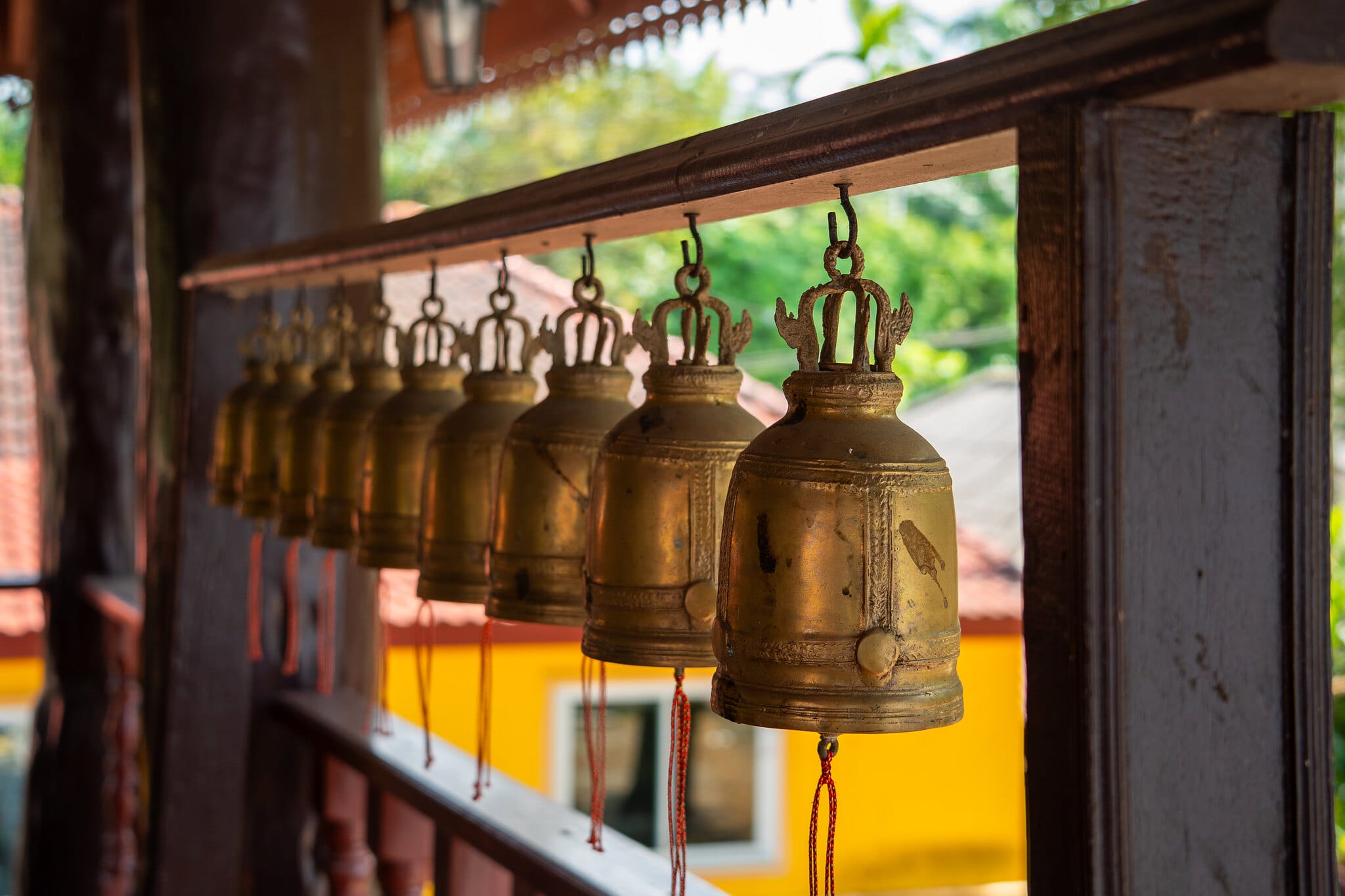 Rangée de cloches de mérite en laiton le long d'une allée de temple bouddhiste près de Khao Lak