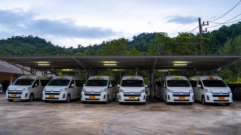 Khao Lak to Surat Thani Transfer - khao lak land discovery van fleet Six Khao Lak Land Discovery transfer vans lined up at the depot, with jungle hills behind